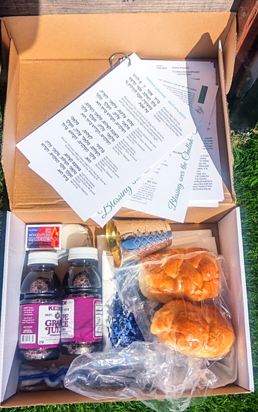 An open Reconnect box with challahs, grape juice, candles and blessing cards